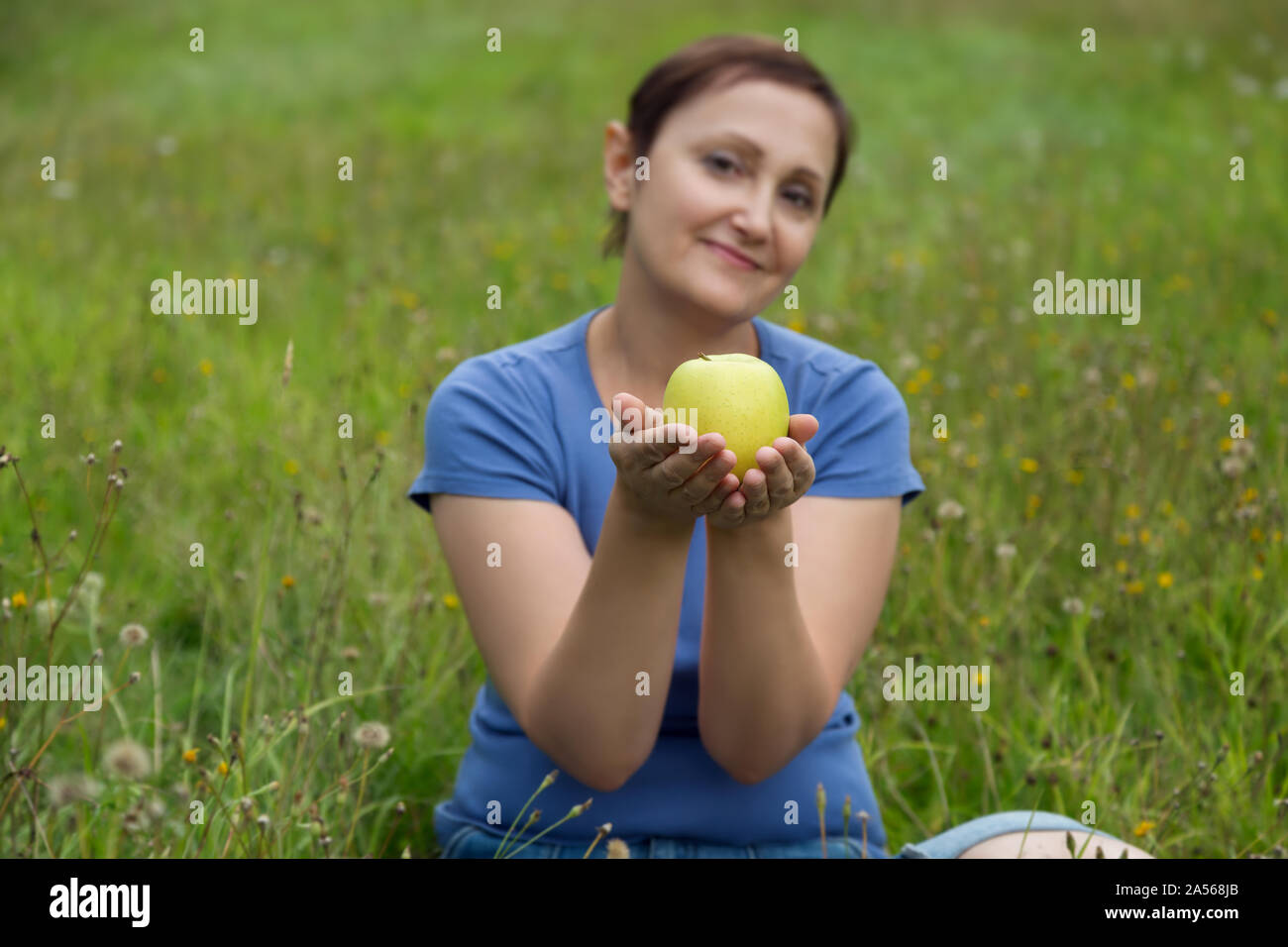 Older woman holding apple. Selective focus on apple fruit. Vegan veggie concept. Stock Photo