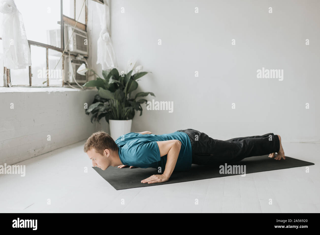 Man doing half plank in yoga studio Stock Photo