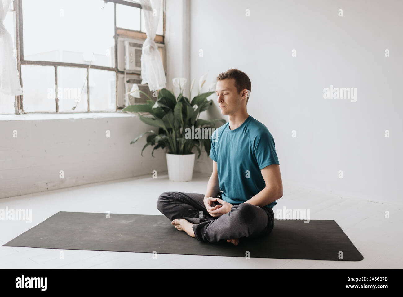 Man sitting in lotus pose in yoga studio Stock Photo