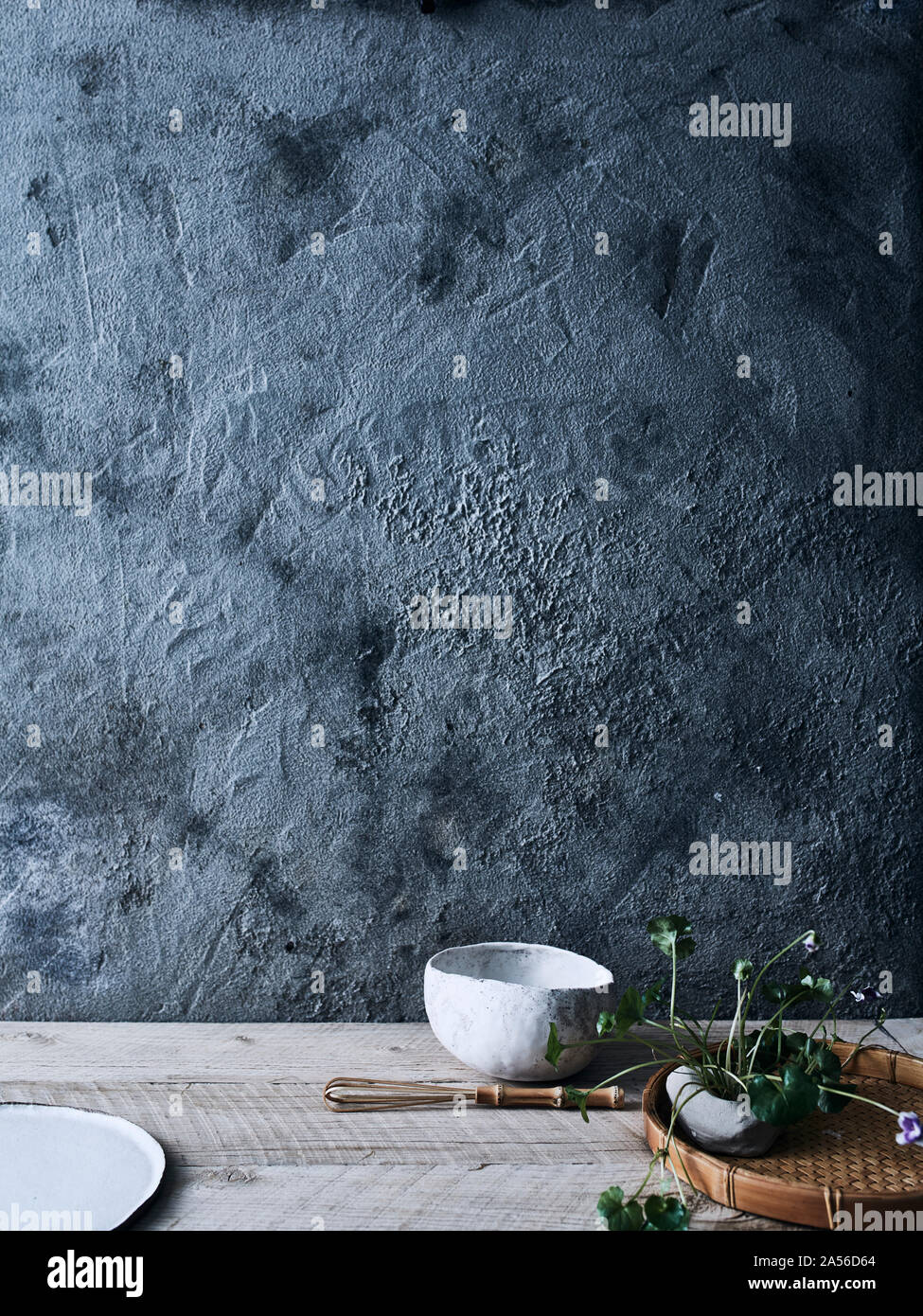 Ceramic bowls and plant against background of unfinished wall Stock Photo