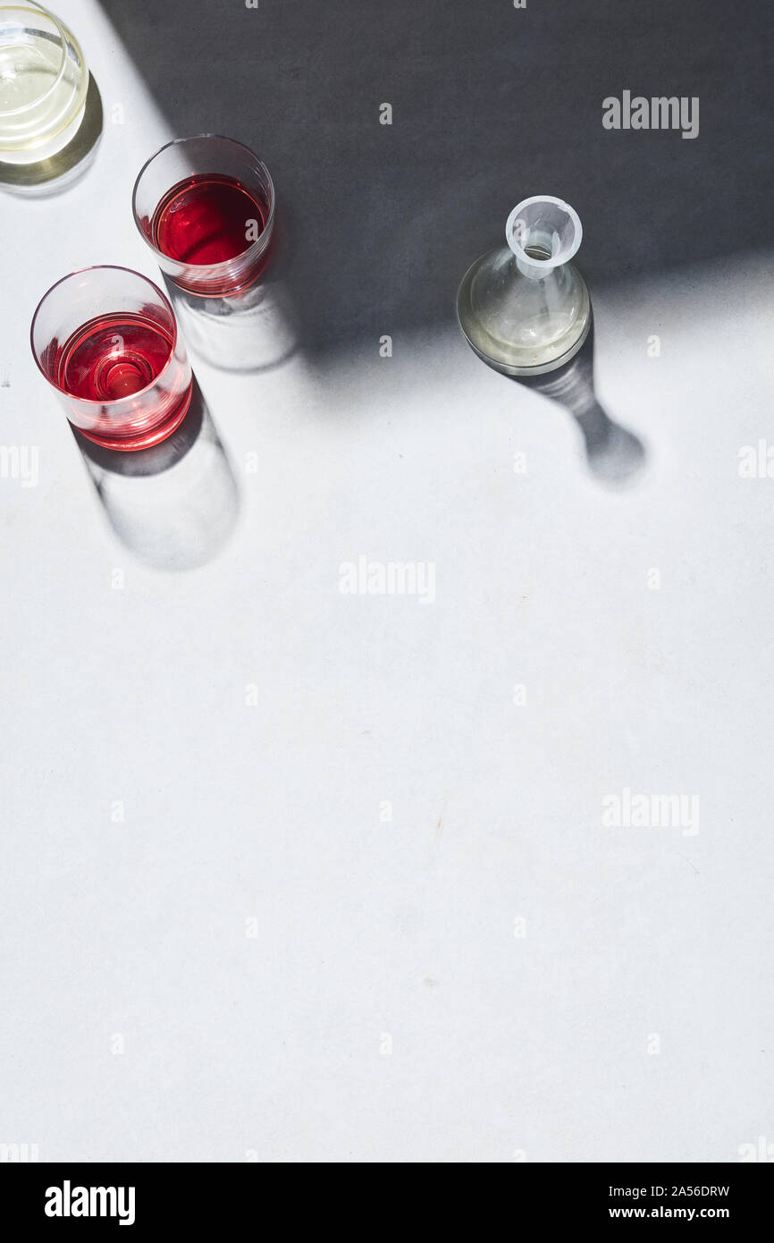 High key still life with glasses of red wine and white white wine on white table, overhead view Stock Photo