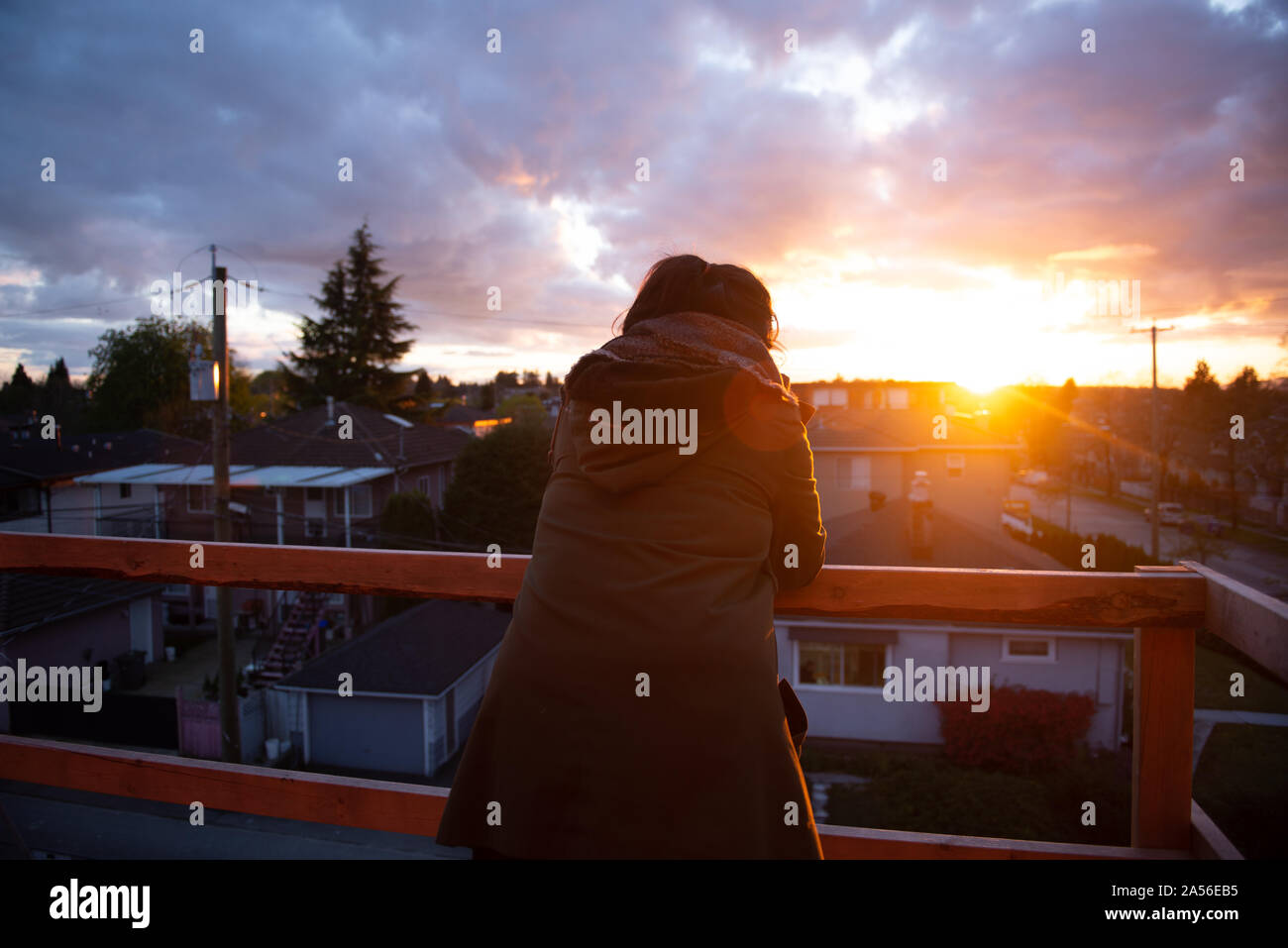 Mid adult woman looking out at sunset from balcony, rear view, Vancouver, British Columbia, Canada Stock Photo