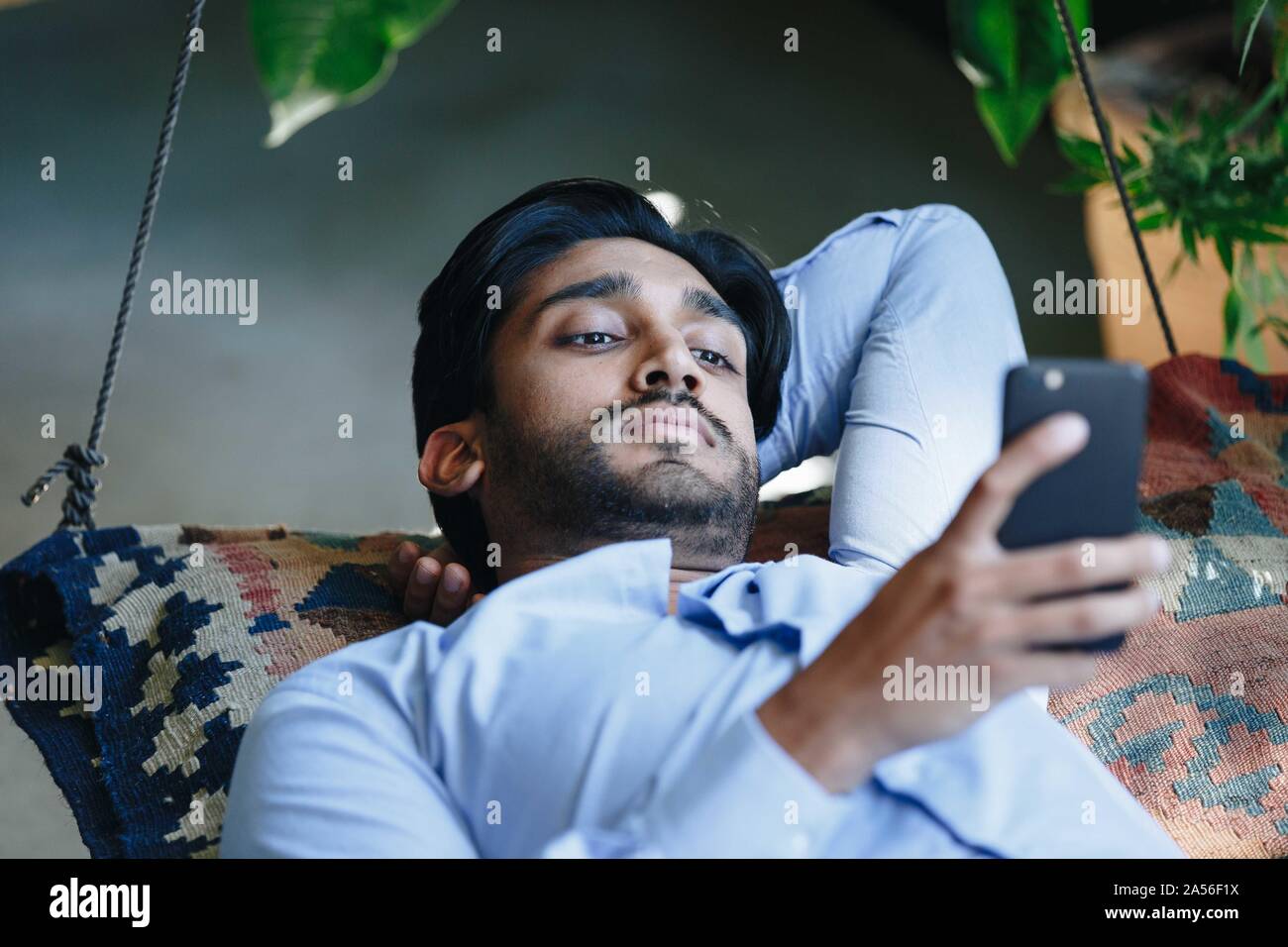 Businessman using cellular phone on swing Stock Photo