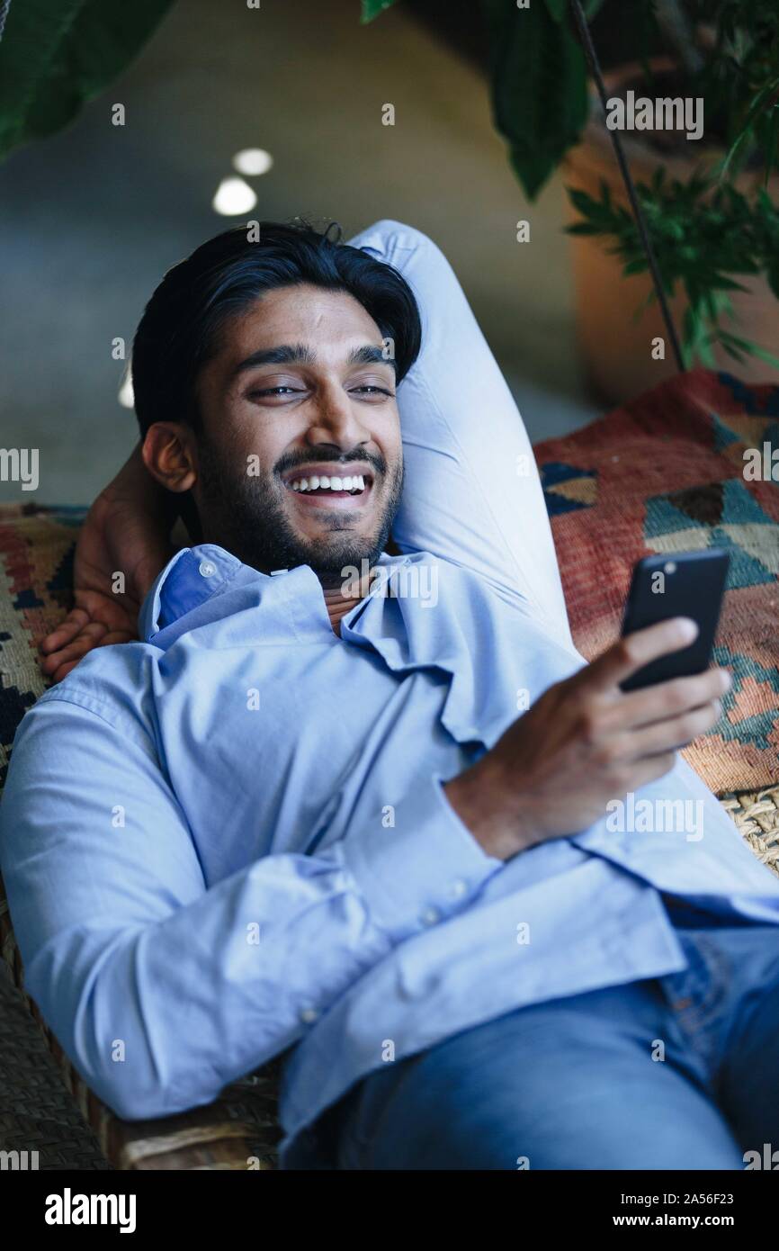 Businessman using cellular phone on swing Stock Photo
