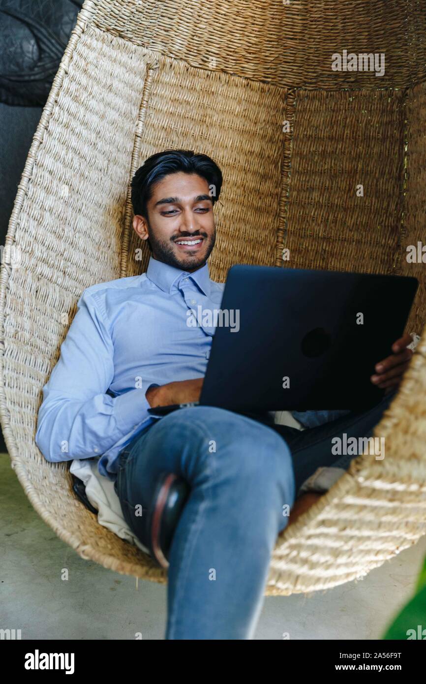 Businessman using laptop on cane swing chair Stock Photo