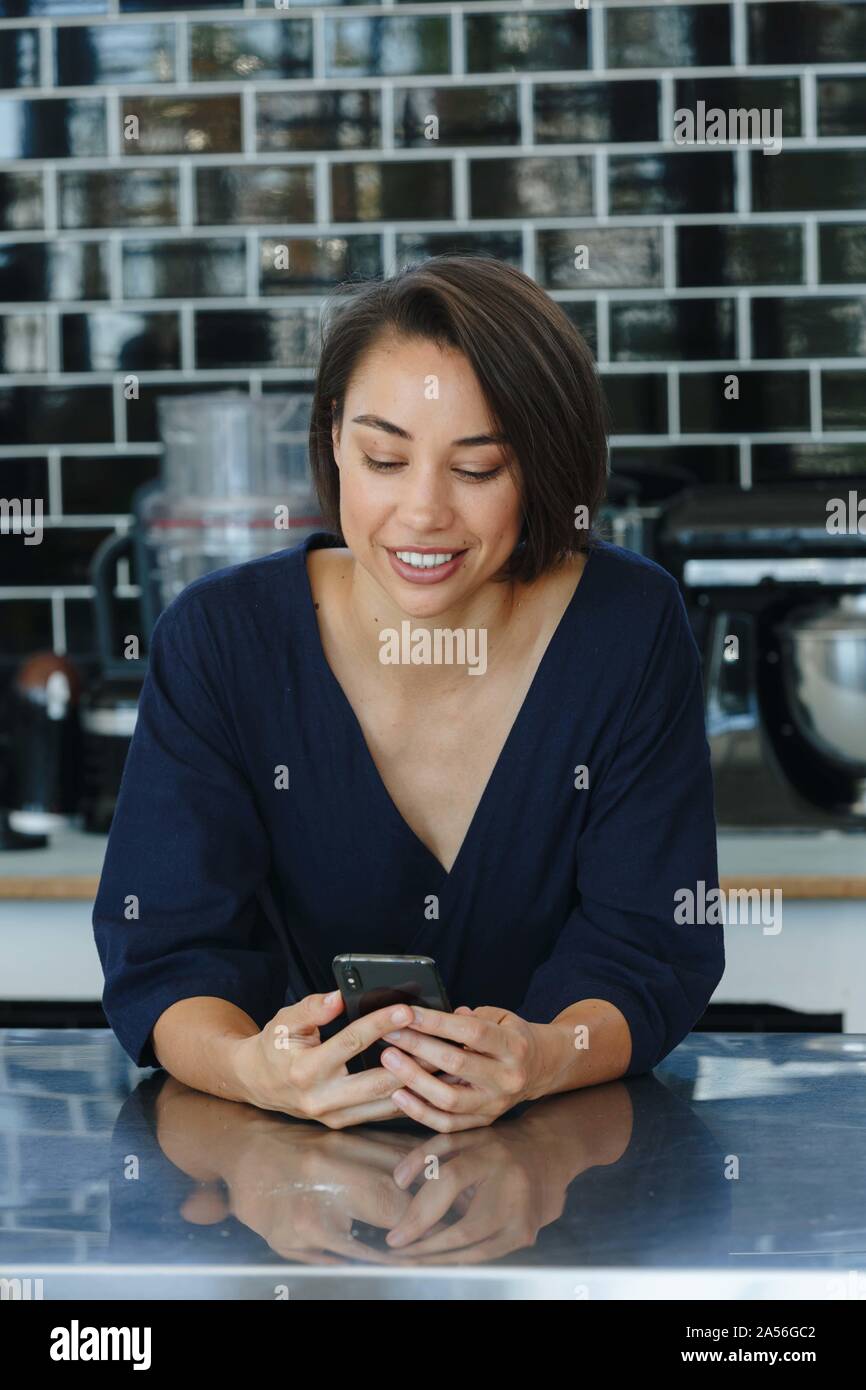 Businesswoman using cellular phone in pantry Stock Photo