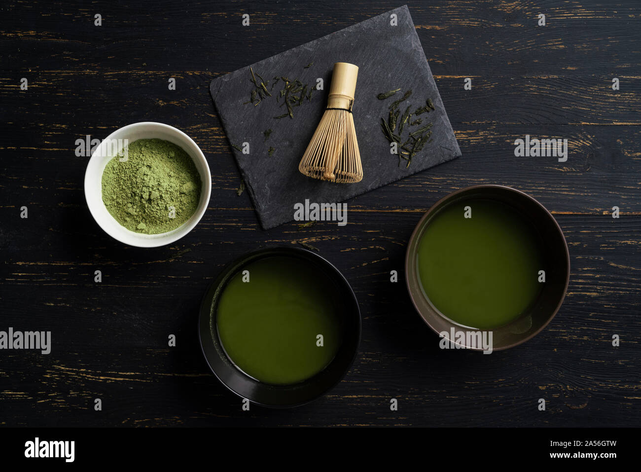 Still life of matcha tea preparation with whisk and bowls of matcha tea and tea powder, overhead view, low key Stock Photo