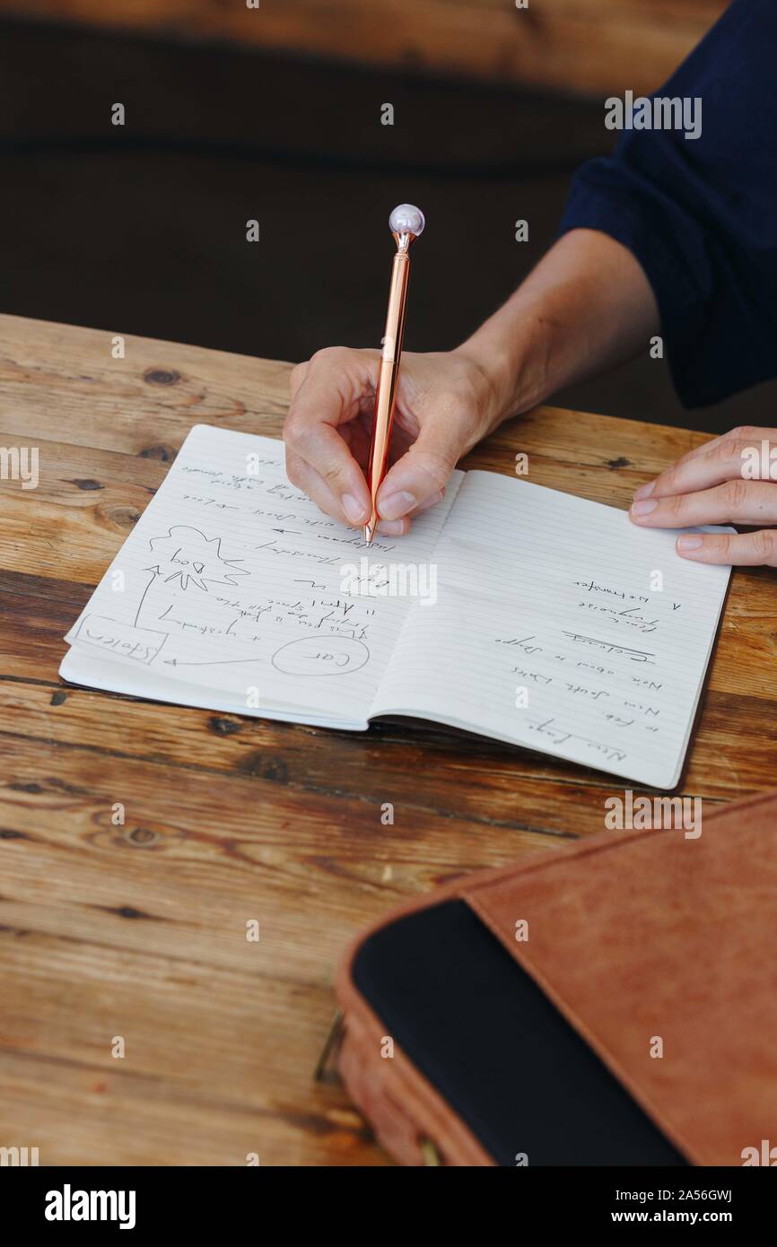 Woman writing in notebook on table top Stock Photo