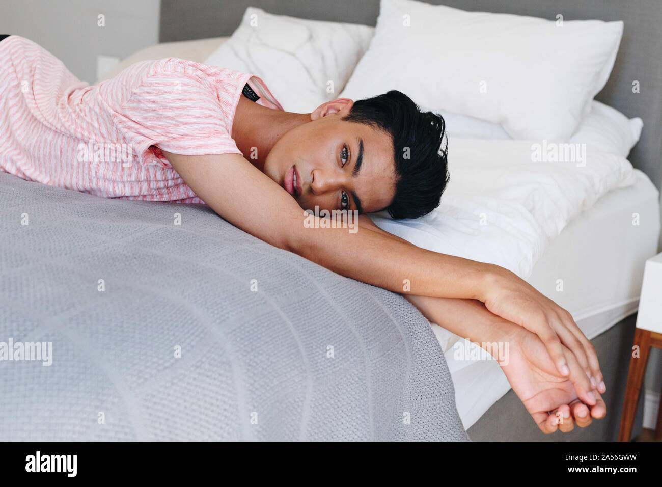 Young man lying on bed looking at camera, portrait Stock Photo