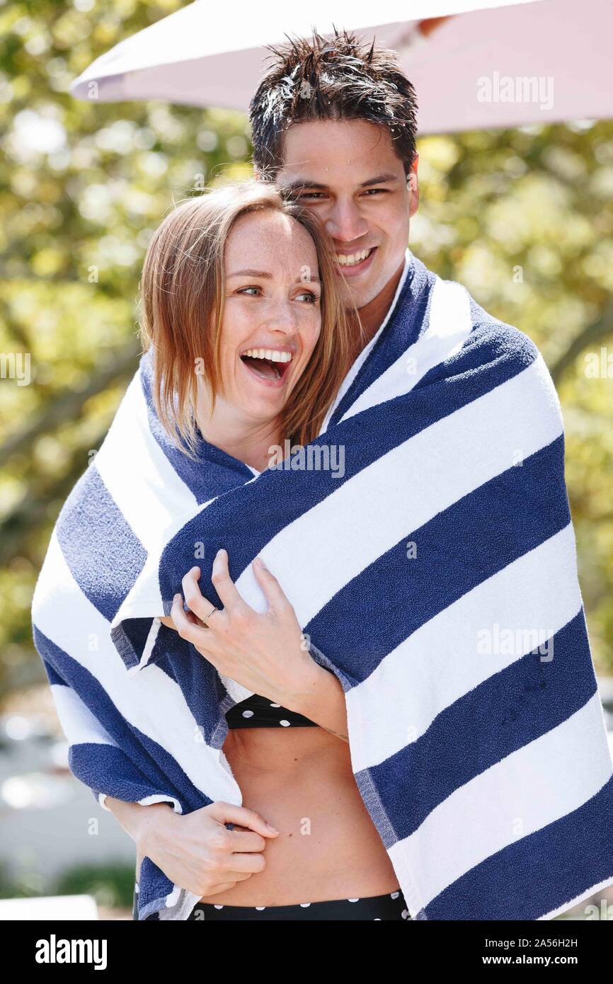 Couple wrapped in striped towel enjoying sun Stock Photo