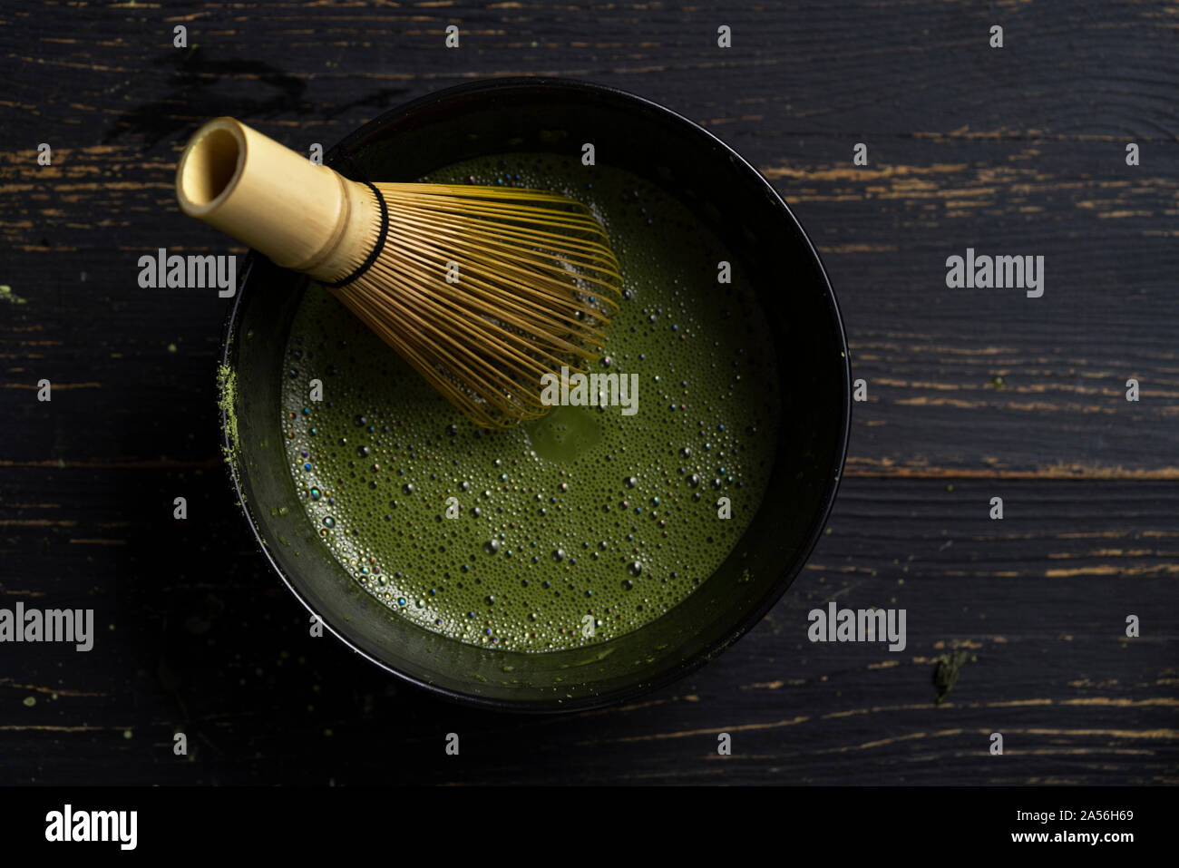 Still life of matcha tea preparation with whisk in bowl of matcha tea, overhead view, low key Stock Photo
