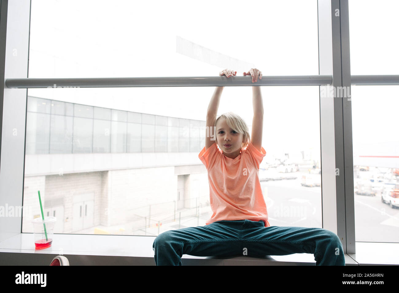 Boy holding handrail in airport window seat, three quarter length portrait Stock Photo