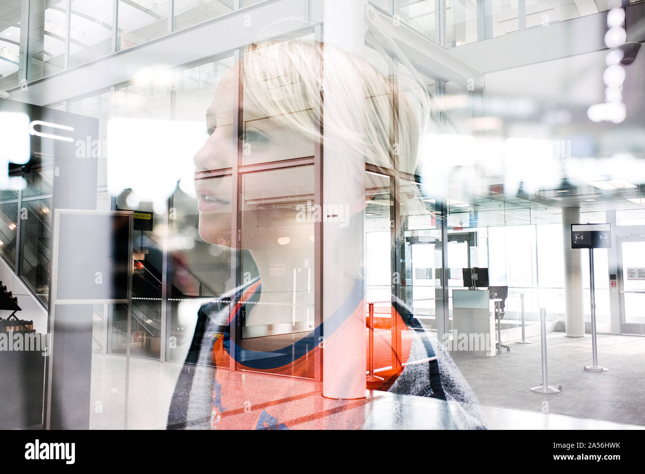 Blond haired boy gazing through window in airport, head and shoulders Stock Photo