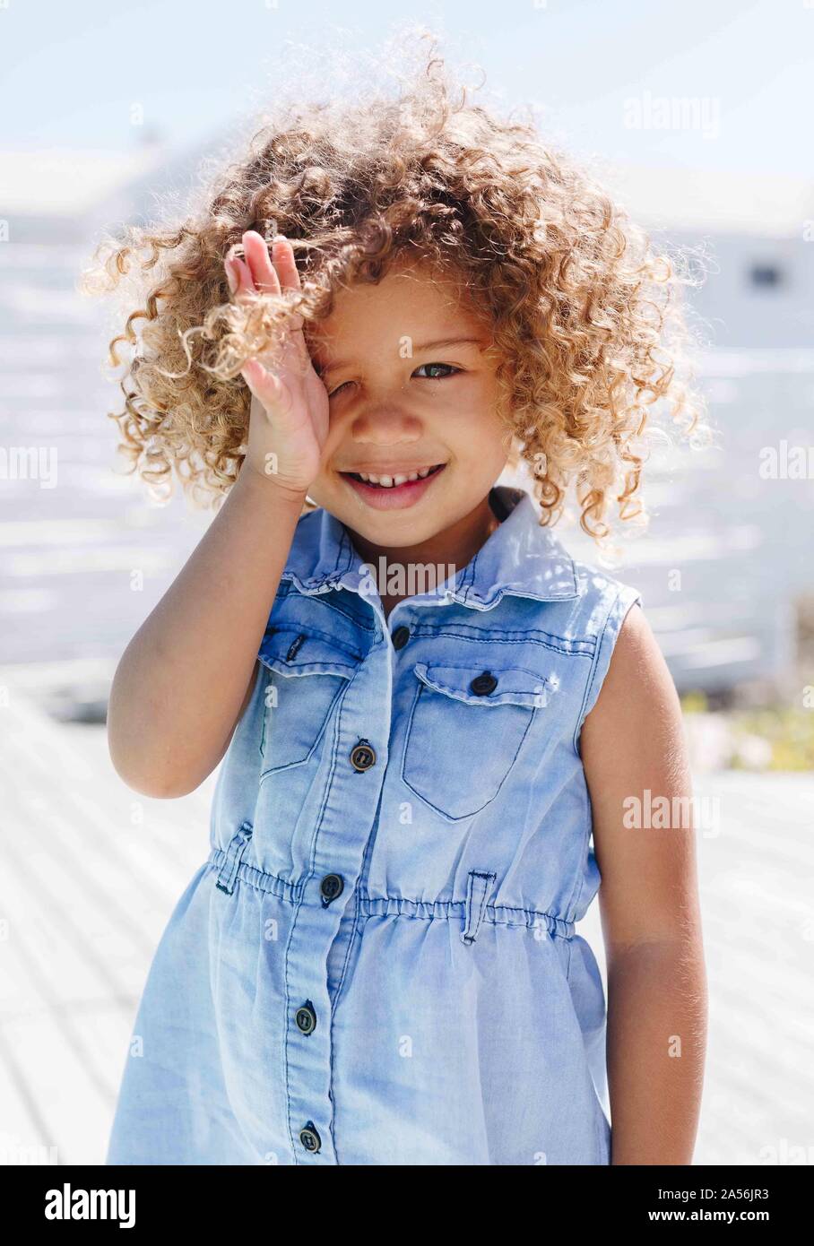 Little girl rubbing eye on sunny day Stock Photo