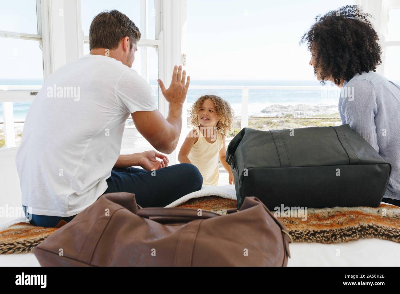 Woman watching husband giving high five to daughter in beach house Stock Photo
