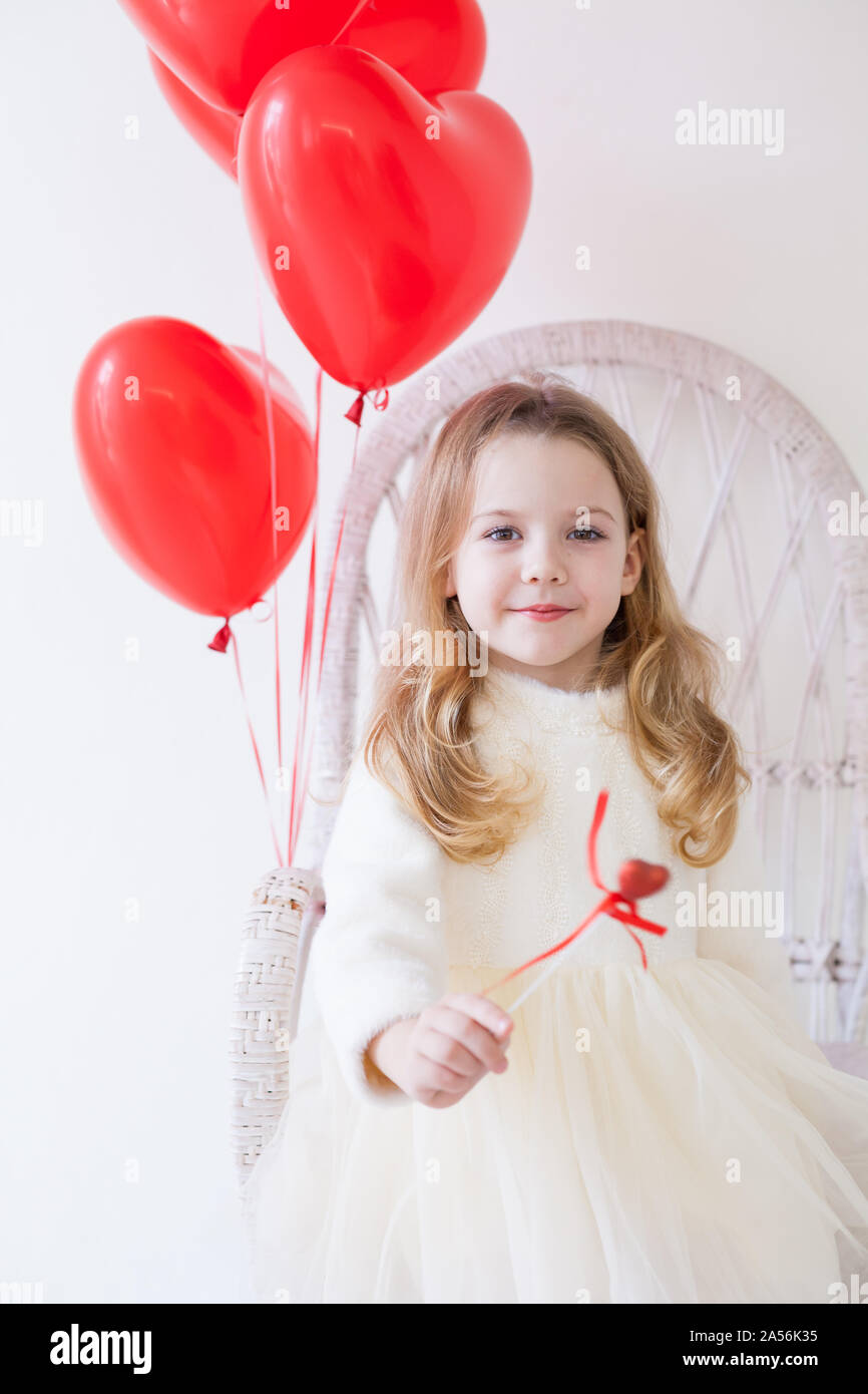 Girl sits on a chair in a room with red holiday balloons Stock Photo ...