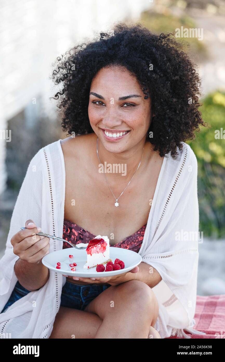 Woman holding plate of raspberry cake, smiling Stock Photo