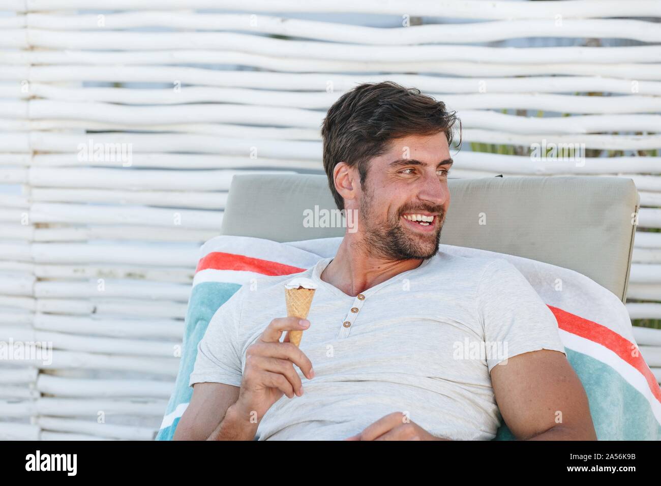 Man enjoying ice cream cone on deckchair Stock Photo