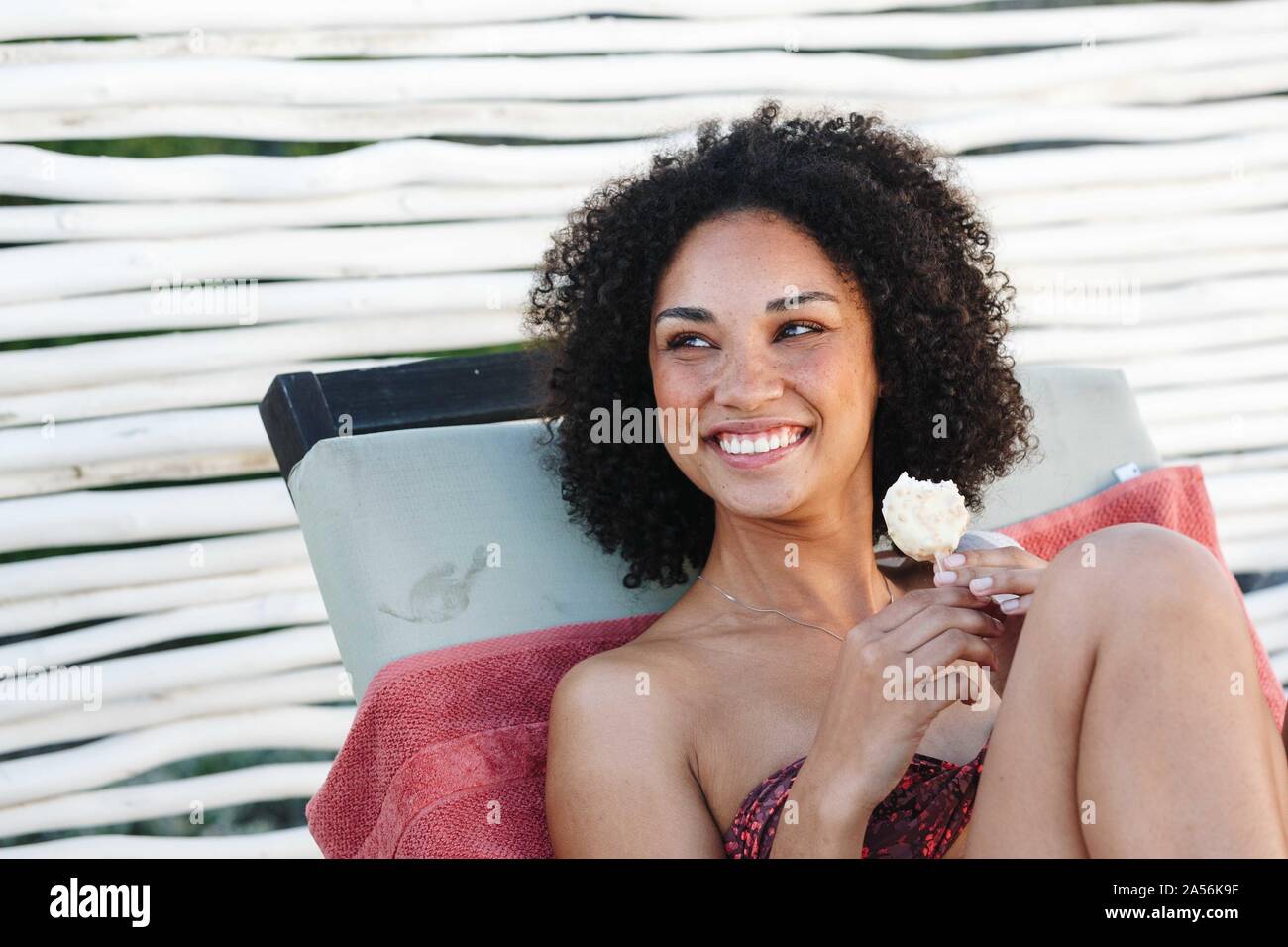 Woman enjoying ice cream on deckchair Stock Photo