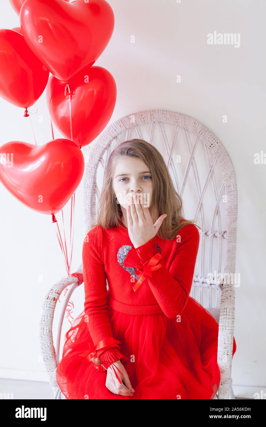 Girl sits on a chair in a room with red holiday balloons Stock Photo ...