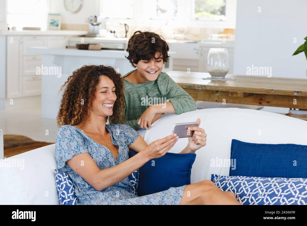 Mother and son smiling at text message on cellphone Stock Photo
