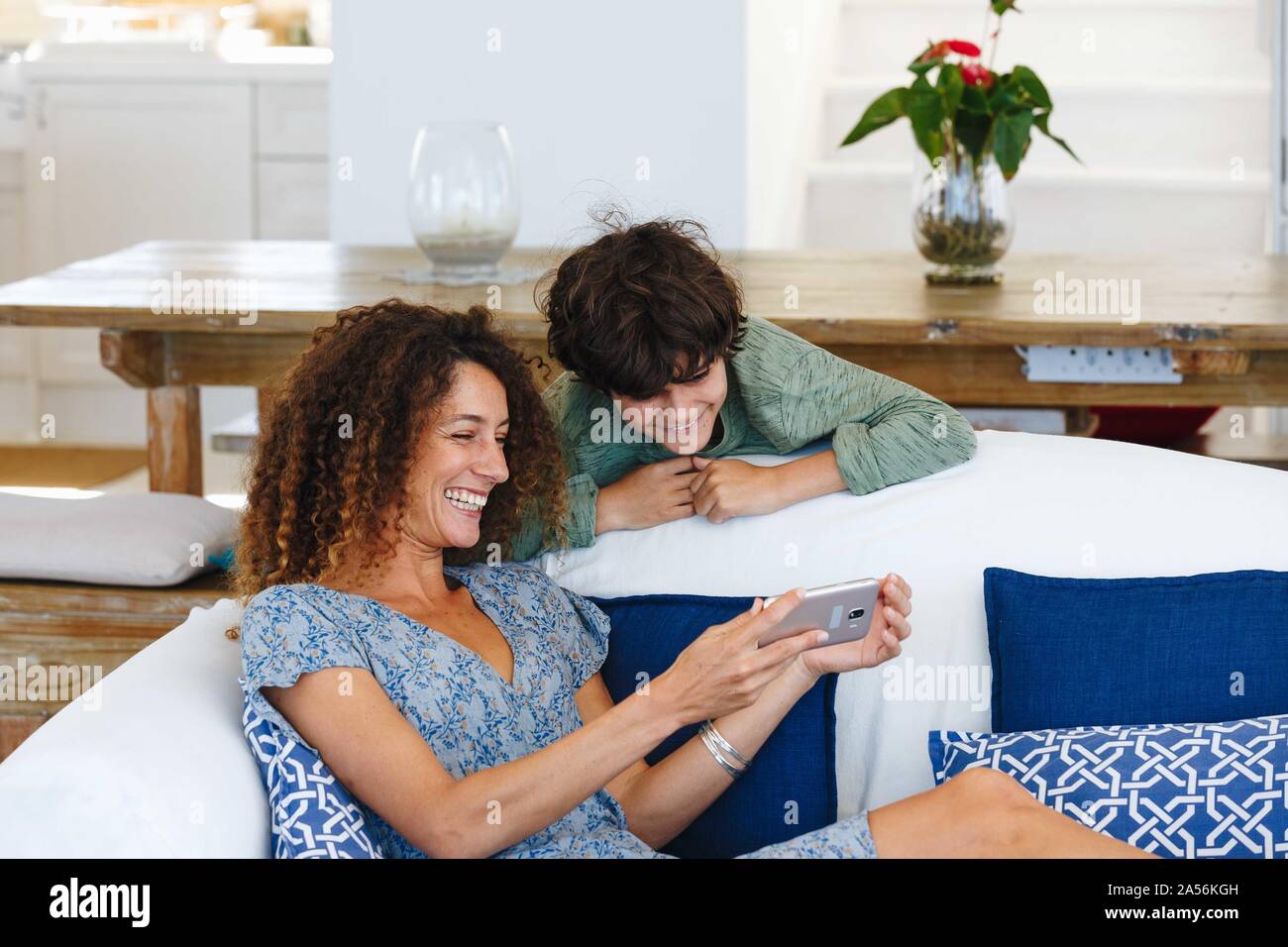 Mother and son smiling at text message on cellphone Stock Photo