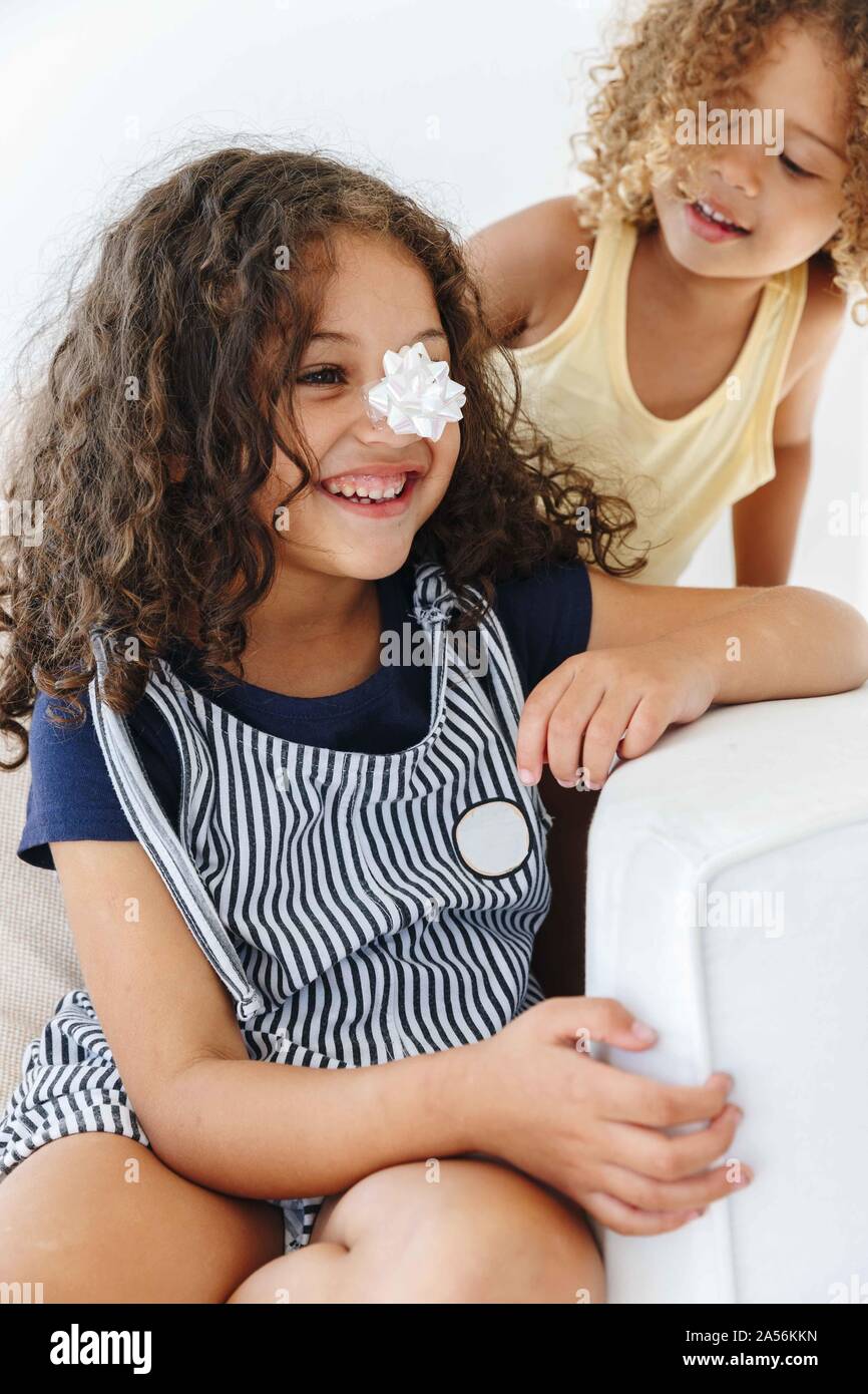 Sisters smiling over paper flower on nose Stock Photo