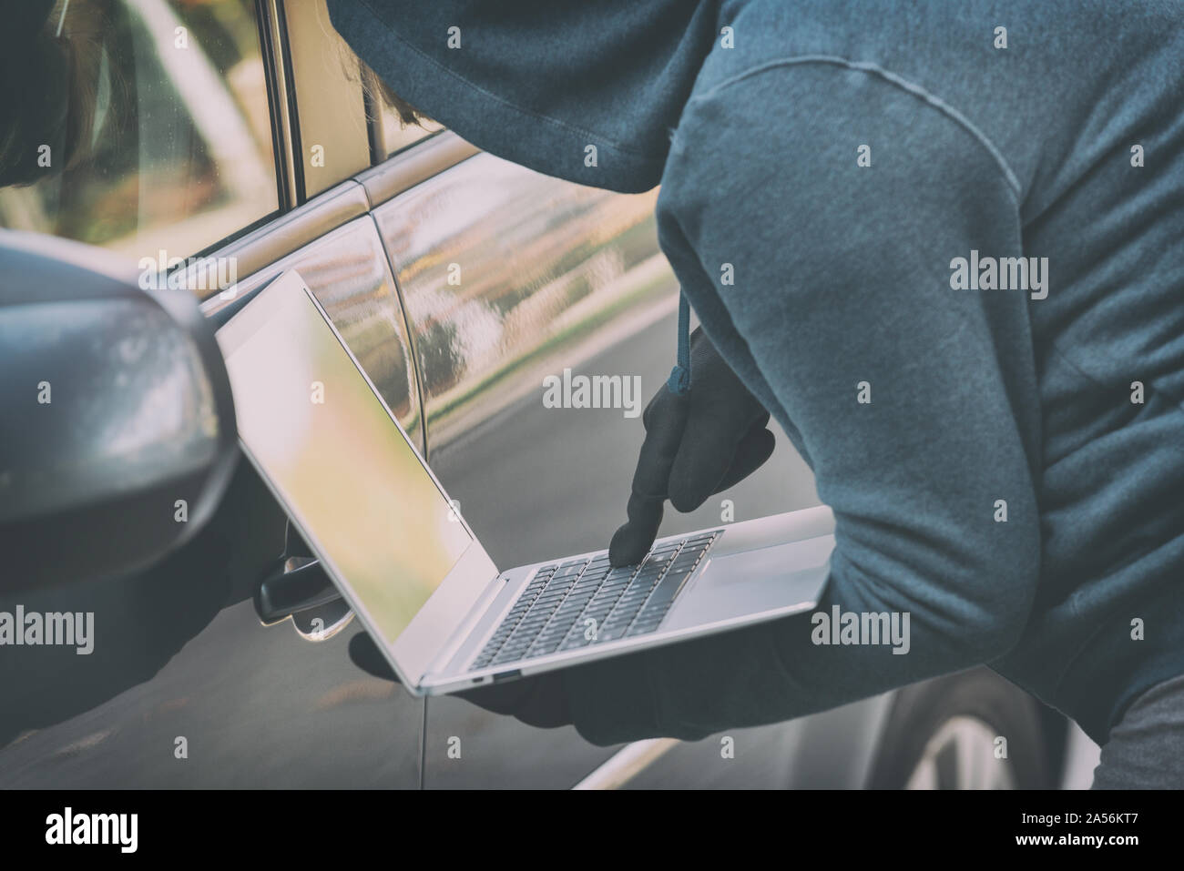Hooded thief tries to break the car's security systems with laptop