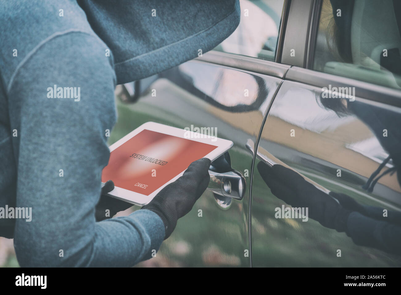 Hooded thief tries to break the car's security systems with tablet