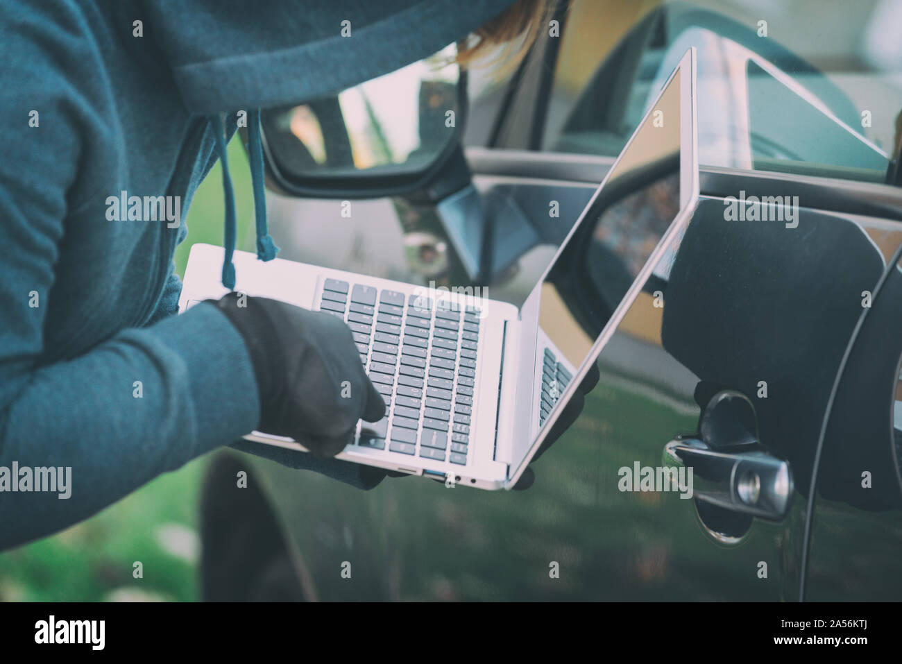 Hooded thief tries to break the car's security systems with laptop