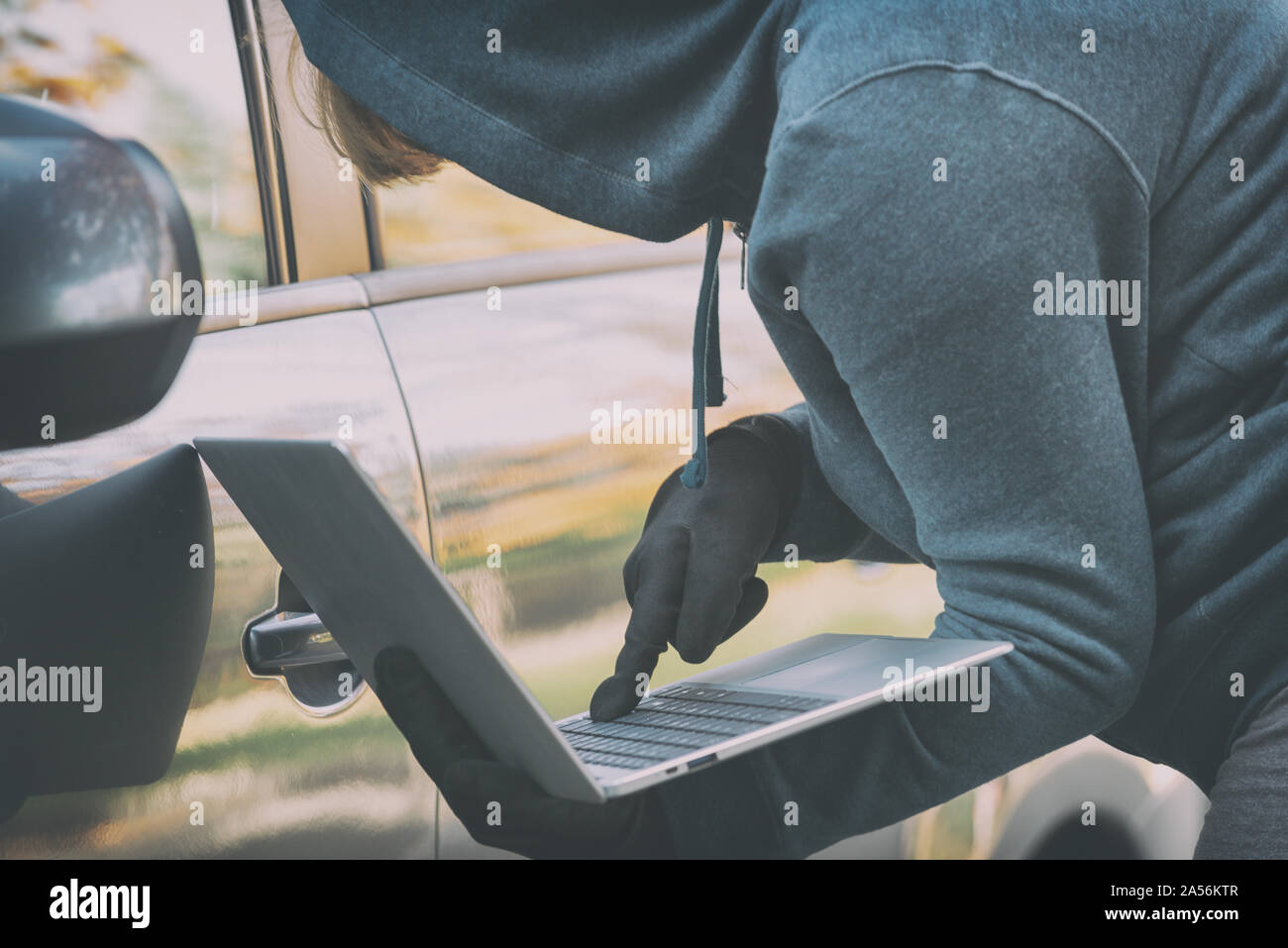 Hooded thief tries to break the car's security systems with laptop