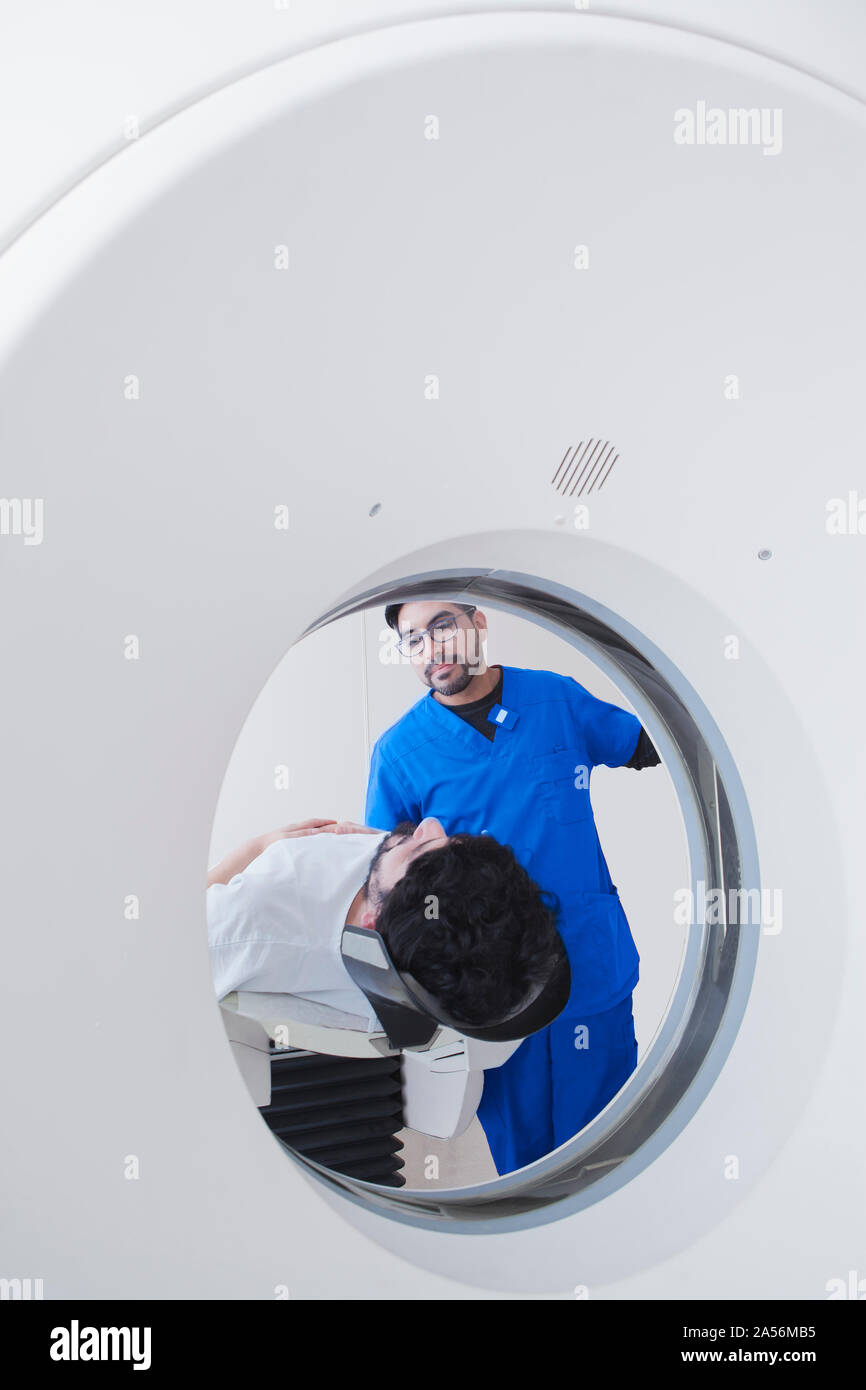 Young male radiographer operating operating CT scanner in radiology