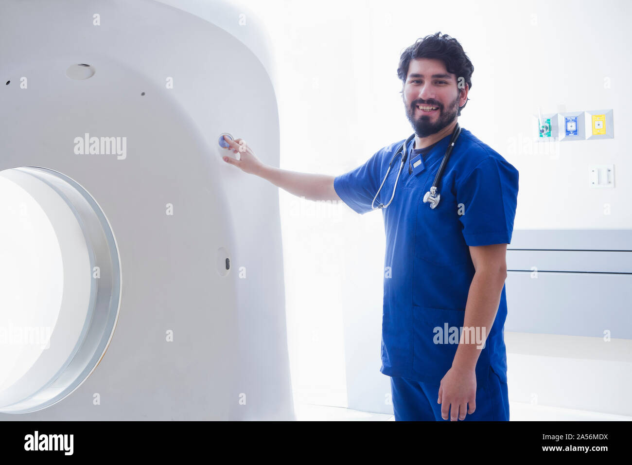 Young male radiographer operating CT scanner in radiology department, portrait Stock Photo