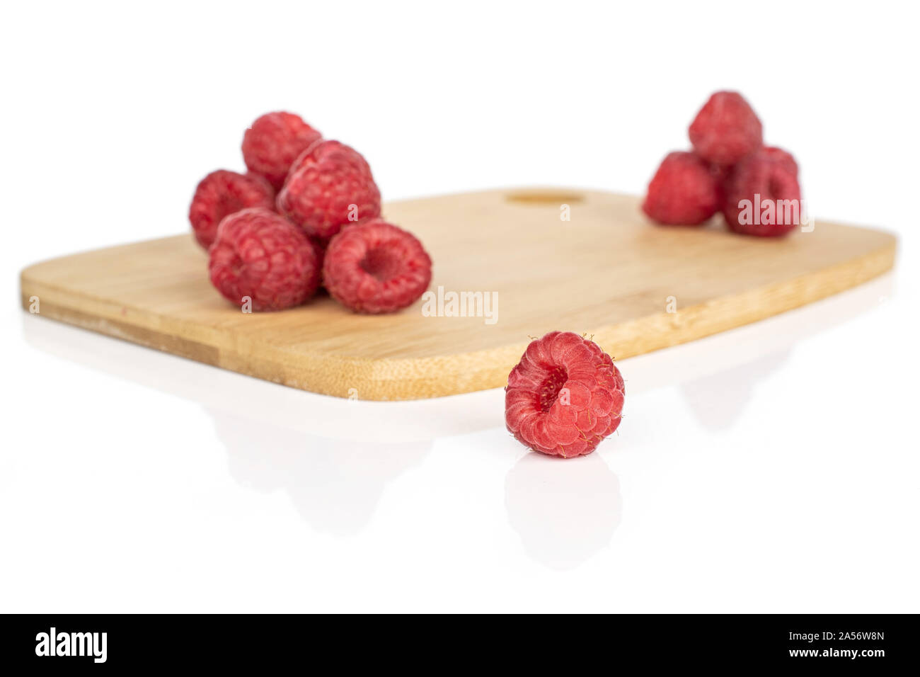 Woodcut Raspberry Group of ten whole fresh red raspberry on bamboo cutting board isolated ...