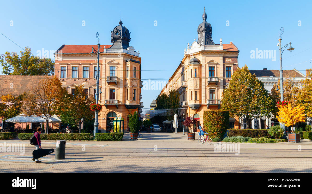 Trees in autumn colors and old buildings along the Piac u. (street) with a view into the Simonffy u. on a sunny day. Debrecen, Hungary. Stock Photo