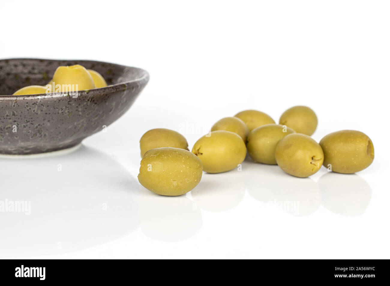 Lot of whole pitted marinated green olive on glazed bowl isolated on white background Stock Photo