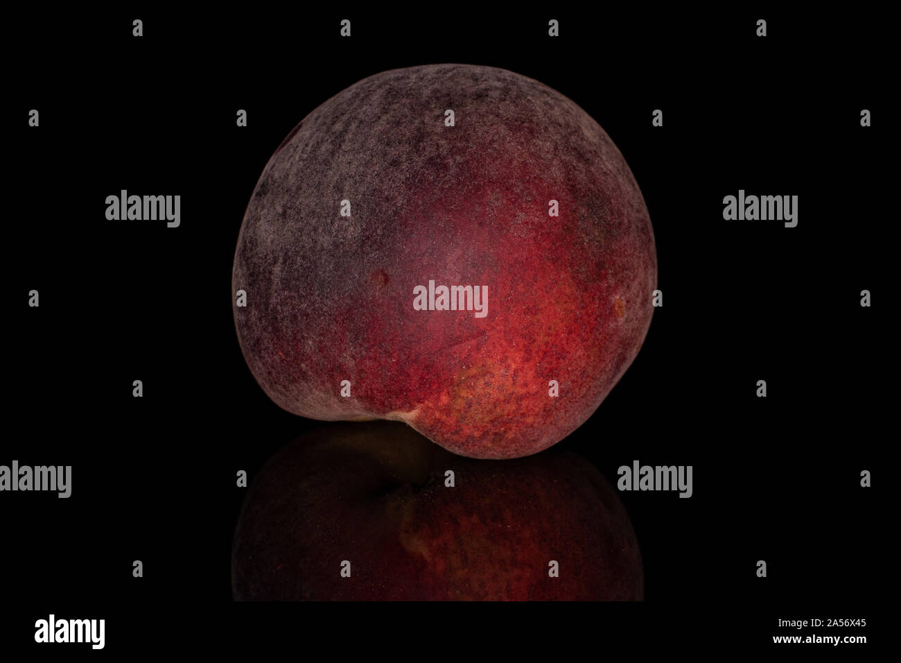 One whole sweet red peach isolated on black glass Stock Photo