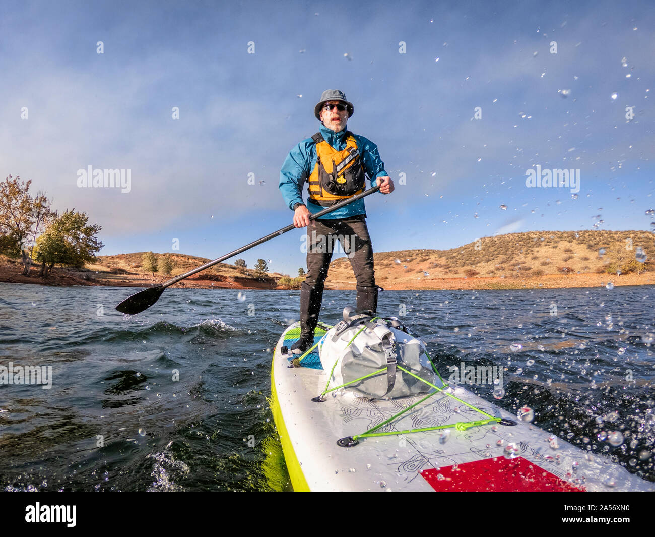 senior man paddling an inflatable stand up paddleboard against head wind on mountain lake - Horsetooth Reservoir , Colorado, in fall scenery Stock Photo