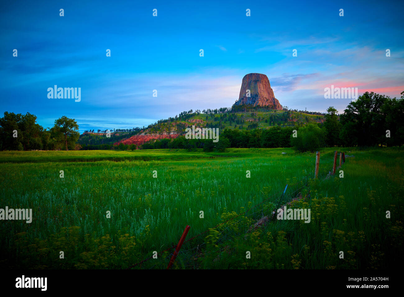 Sunrise at Devils Tower National Monument with wired fence in the foreground. Stock Photo