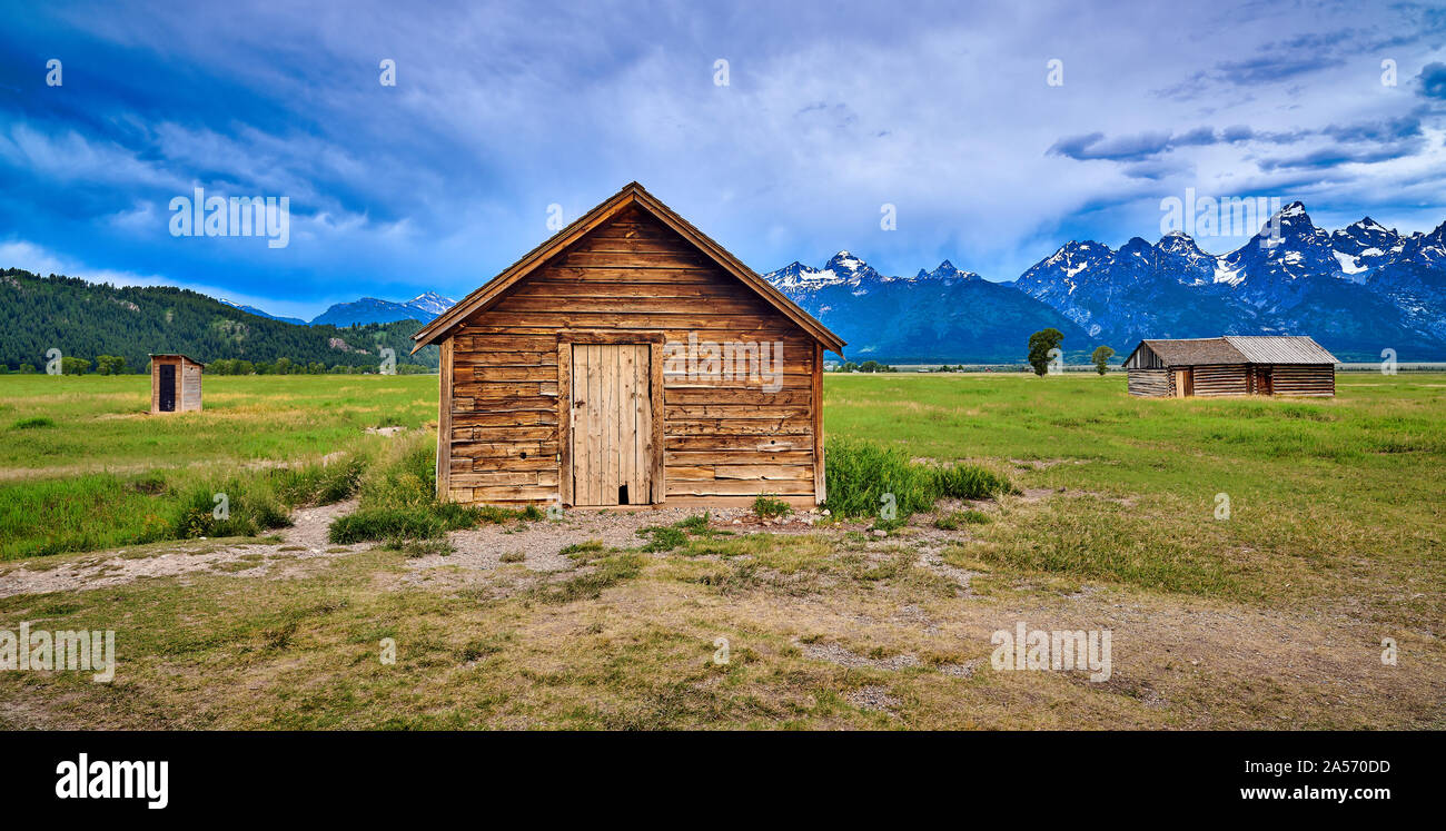 Storm clouds with outhouse, pumphouse and granary. Mormon Row, Grand Teton National Park. Stock Photo