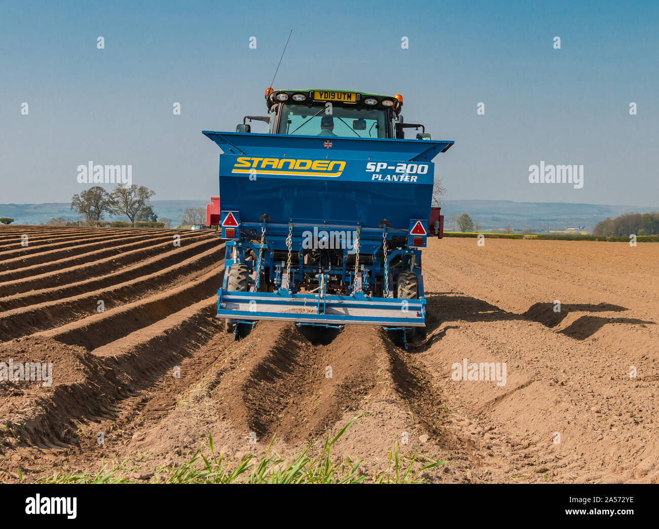 A John Deere tractor and Standen potato planter at work in spring sunshine Stock Photo