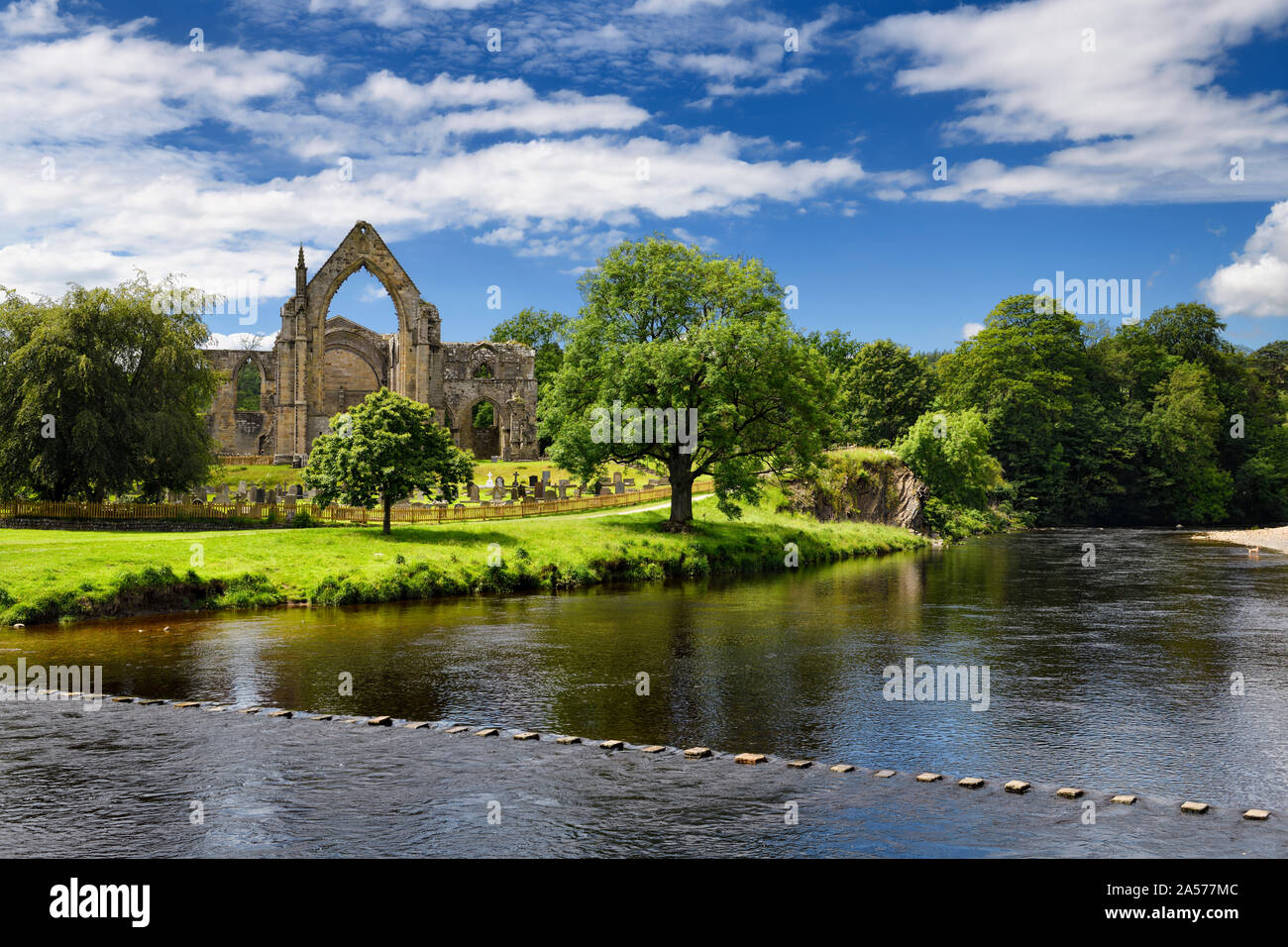 12th century Augustinian Bolton Priory church ruins on the River Wharfe with stepping stones at Bolton Abbey England Stock Photo