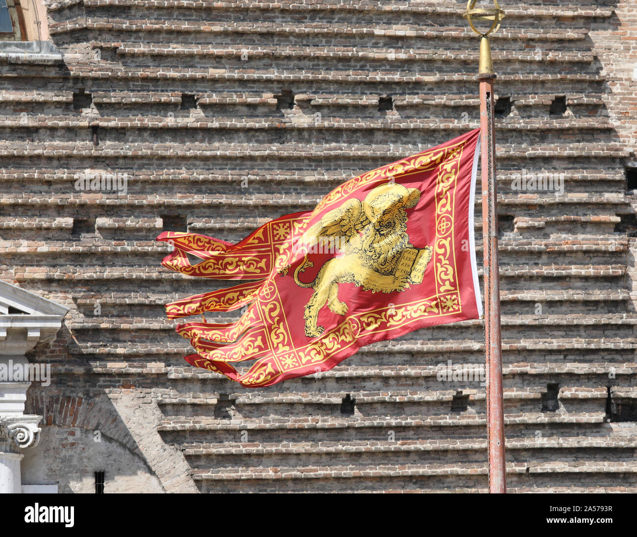 Veneto Region Flag also called Flag of Serenissima Repubblica with winged lion and the wall of bricks in background Stock Photo