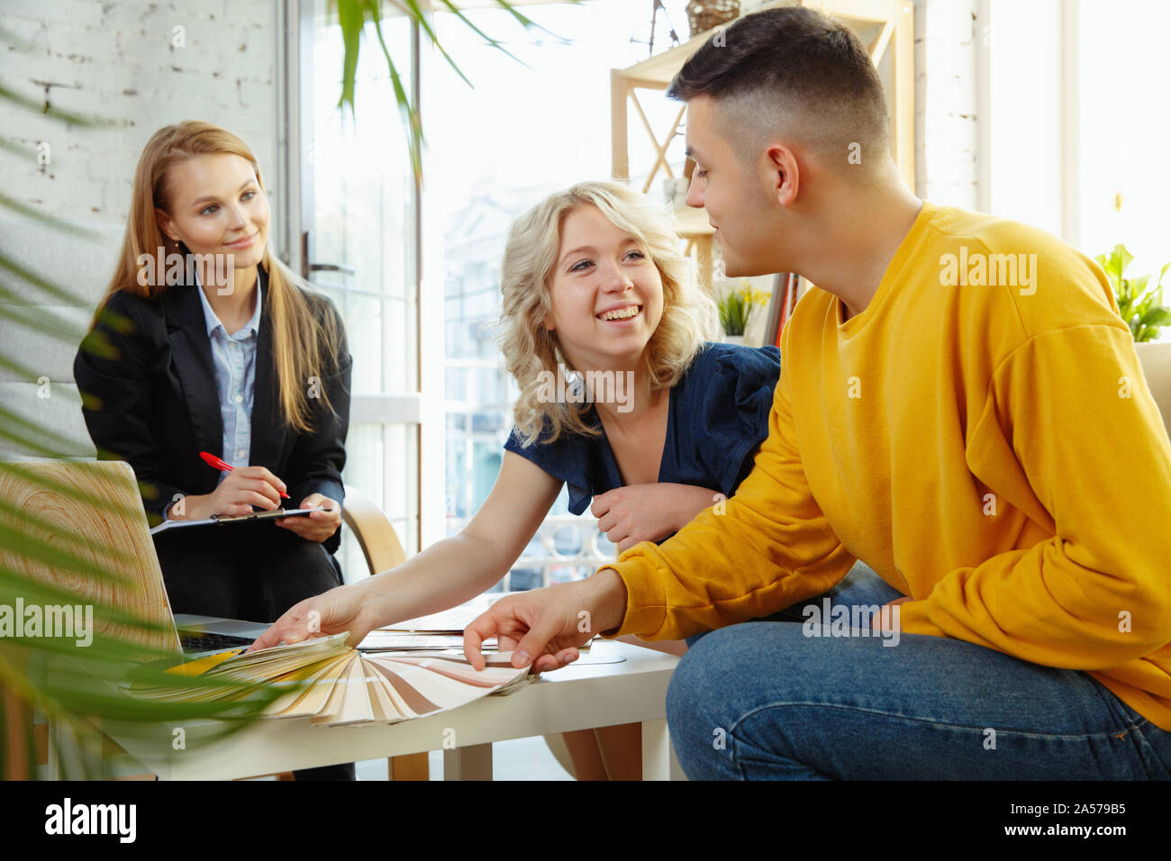 Interior designer working with young couple. Lovely family and ...