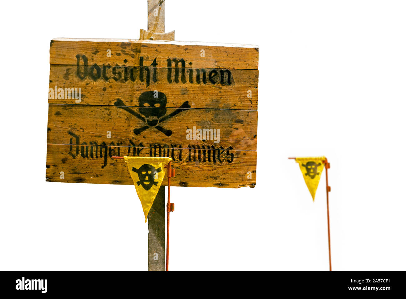 German World War Two wooden Vorsicht Minen / Caution Land Mines warning sign and marker flags marking minefield / minefield against white background Stock Photo