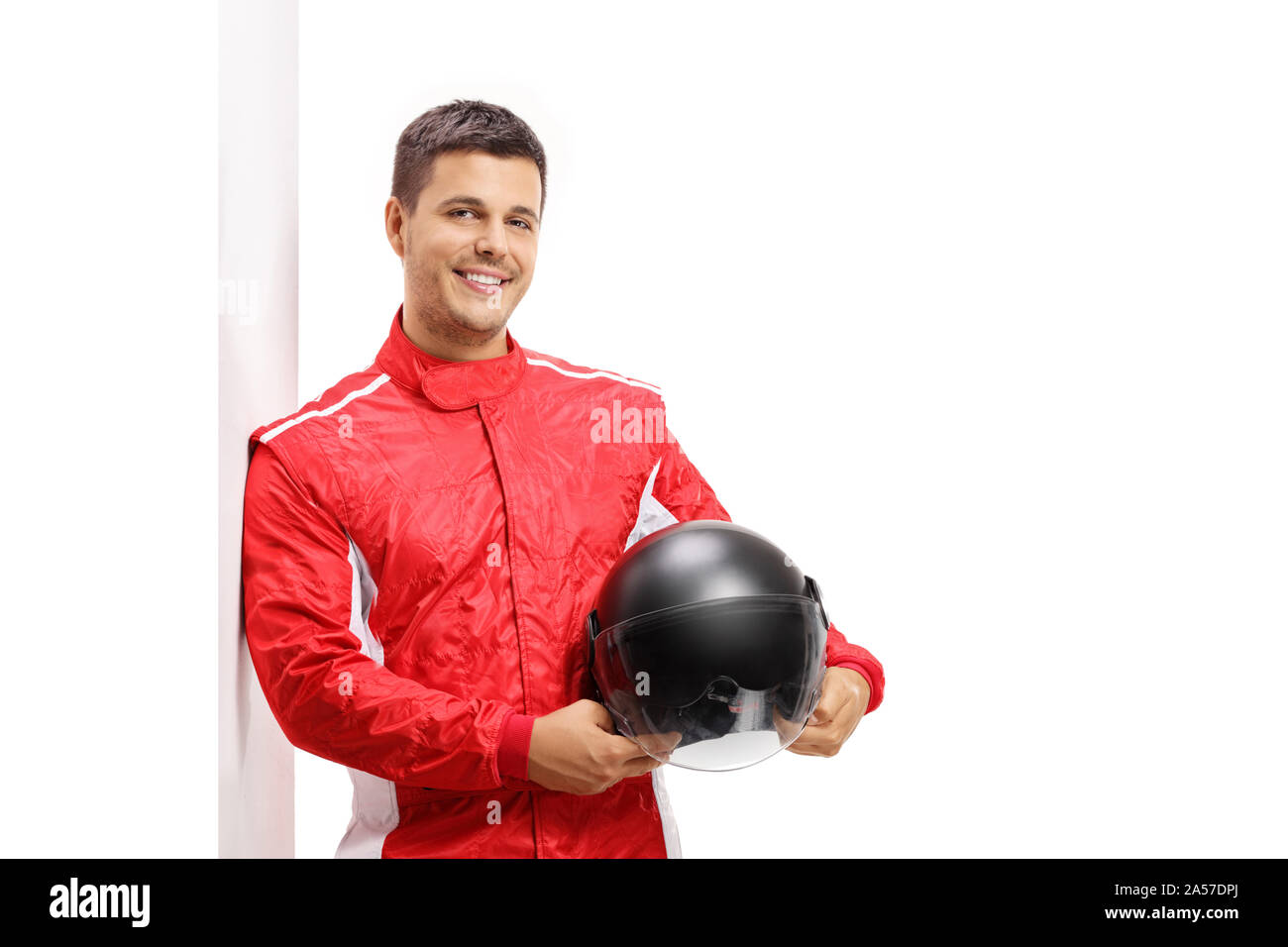 Car racer holding a helmet and leaning against a wall isolated on white background Stock Photo