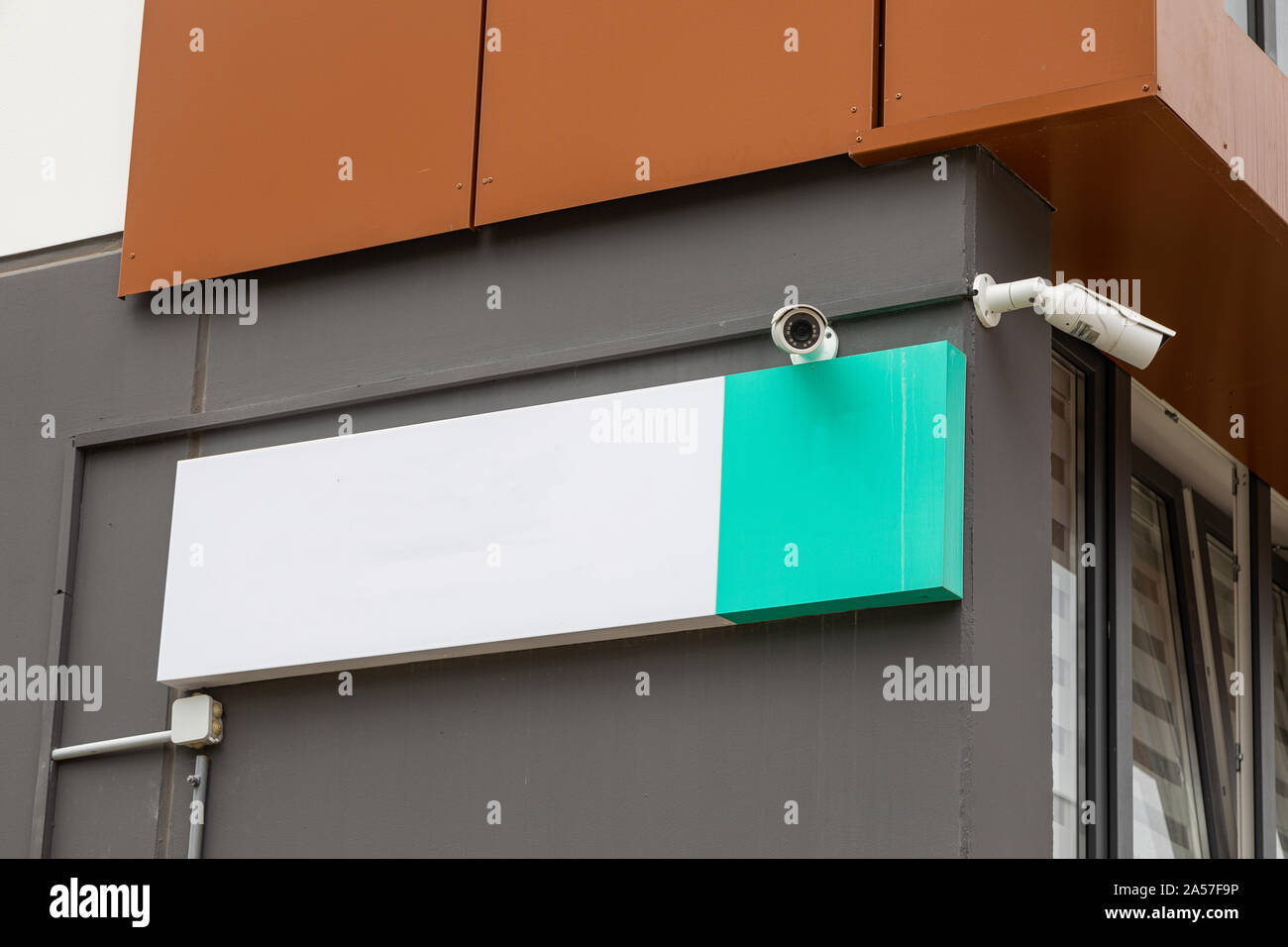 Two security cameras on new house building with white empty tablet