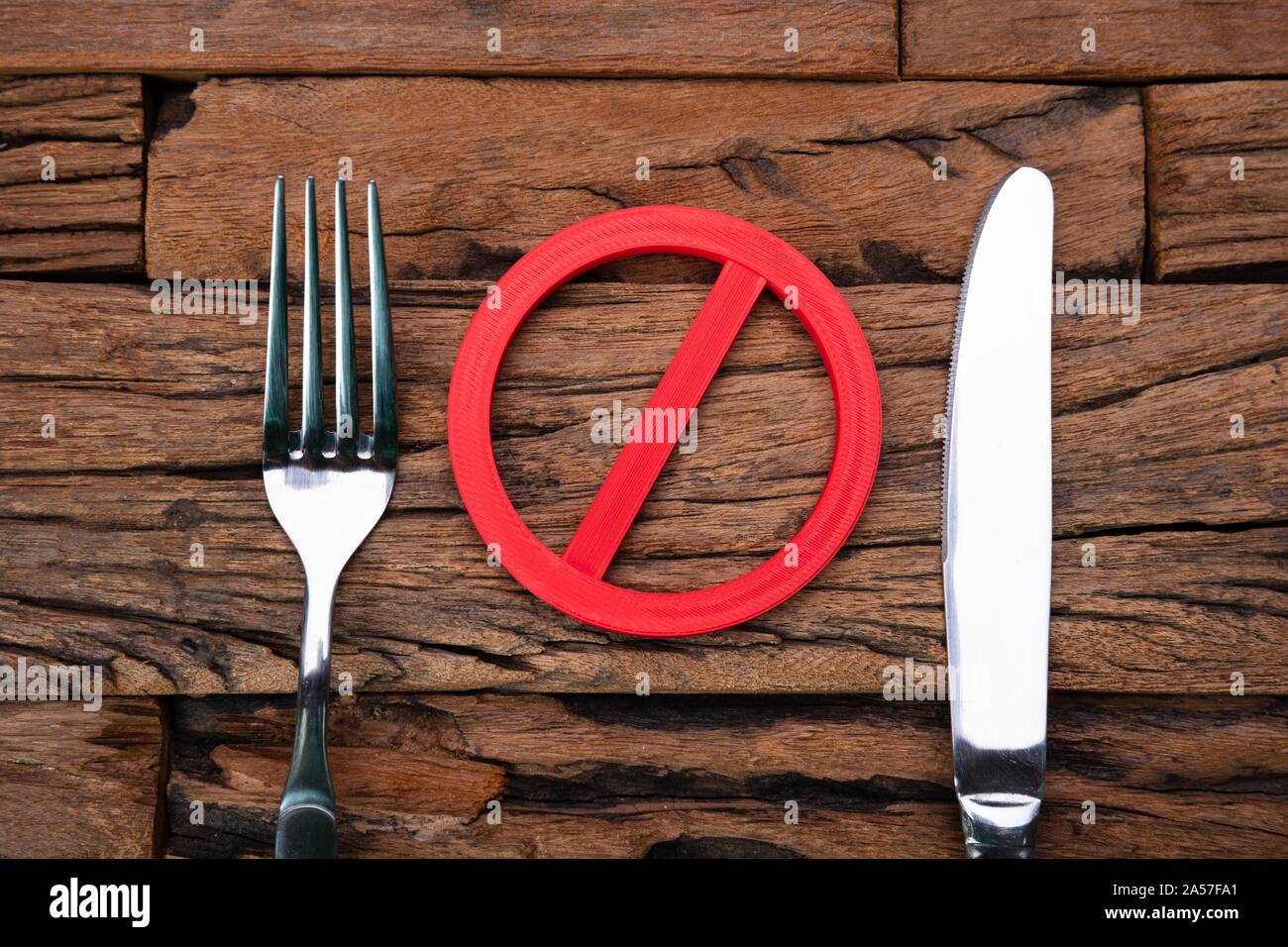 Stop Sign Near Fork And Knife On Wooden Table Stock Photo