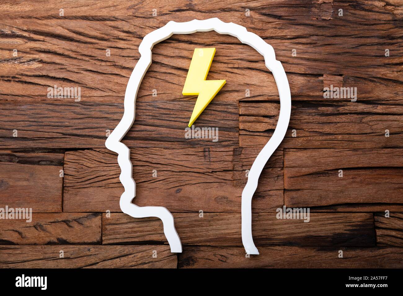 Lightning Idea Inside Head Silhouette On Wooden Desk Stock Photo