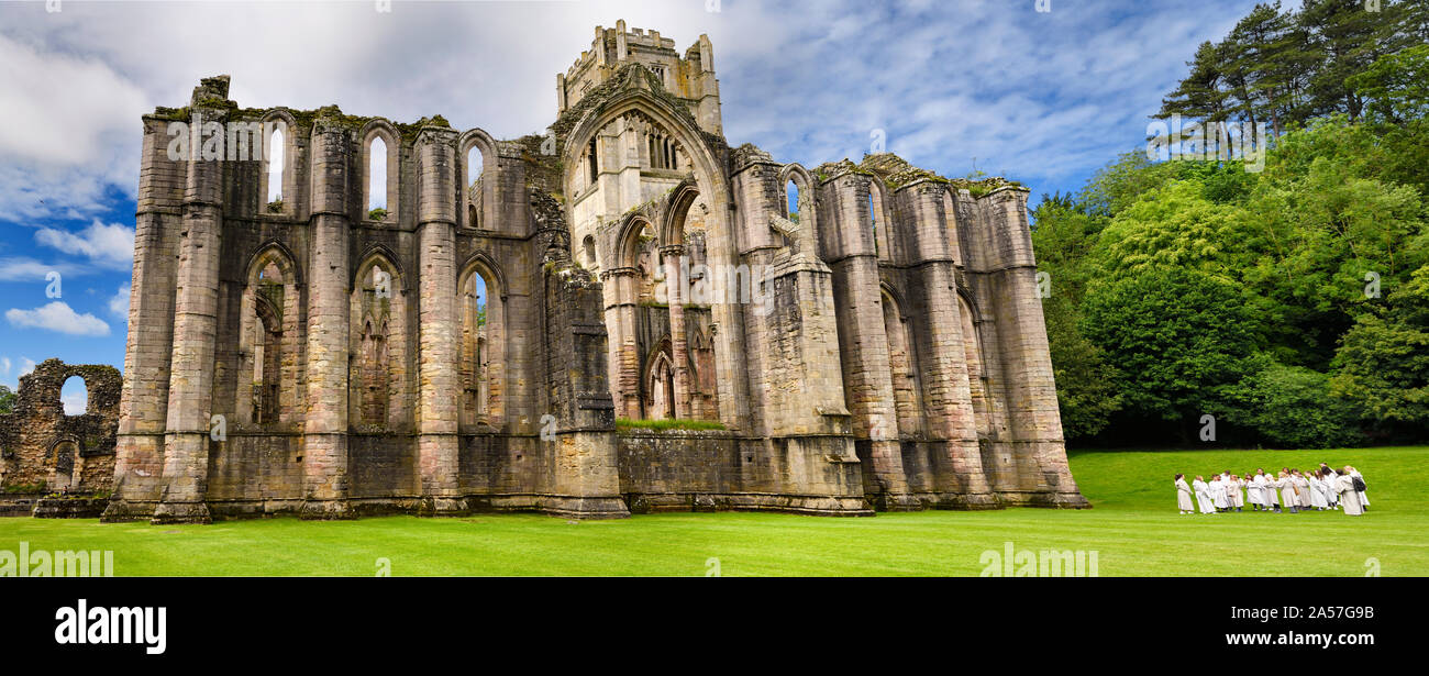 Panorama of Fountains Abbey Cistercian monastery church with tower and Chapel of Altars and group of school children North Yorkshire England Stock Photo